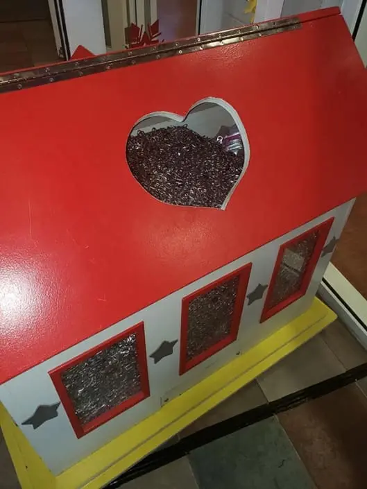 The donation box at the Ronald McDonald House. The lid is closed, but pull-tabs can be seen through the windows on the side of the box, and through the heart-shaped hole in the lid.