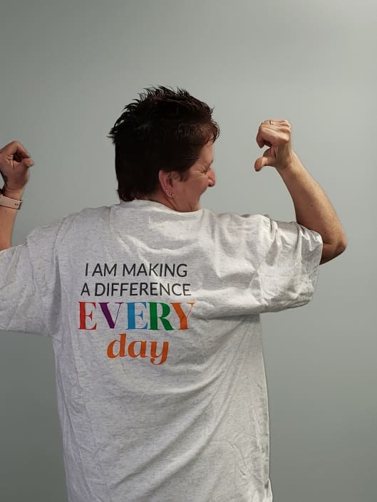 A woman pointing to her tshirt which reads, "I am making a difference every day".
