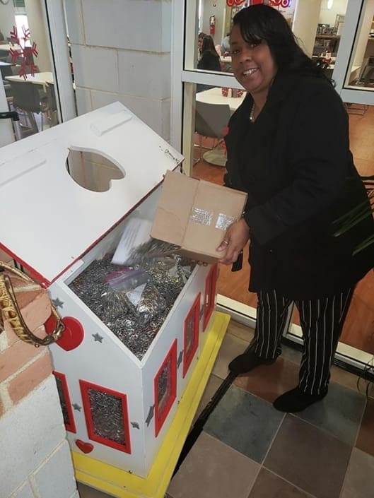 A woman pouring a box of pull-tabs from a can into a donation box at the Ronald McDonald House.